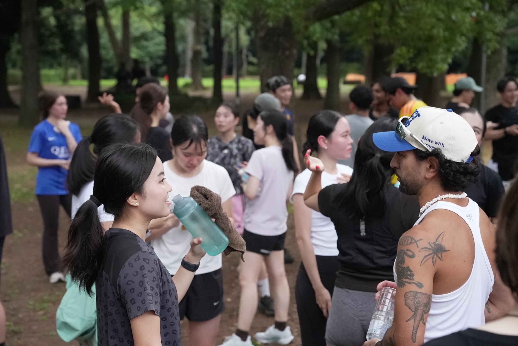 木々に囲まれた公園で、ランニングの仲間と会話を楽しむ様子